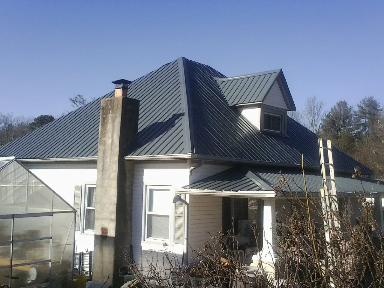 Dark blue standing seam metal roof on a white farmhouse with dormer — Slate & Tile Roof Repair by Roofing Brothers in Waddy
