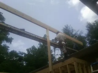 Carpenter setting a ridge beam over a new addition frame — Ice Dam Removal by Roofing Brothers in Waddy