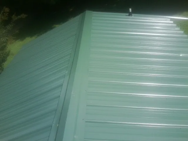 New green metal panels meeting at the ridge of a roof — Flat Roof Repair work by our crew in Waddy