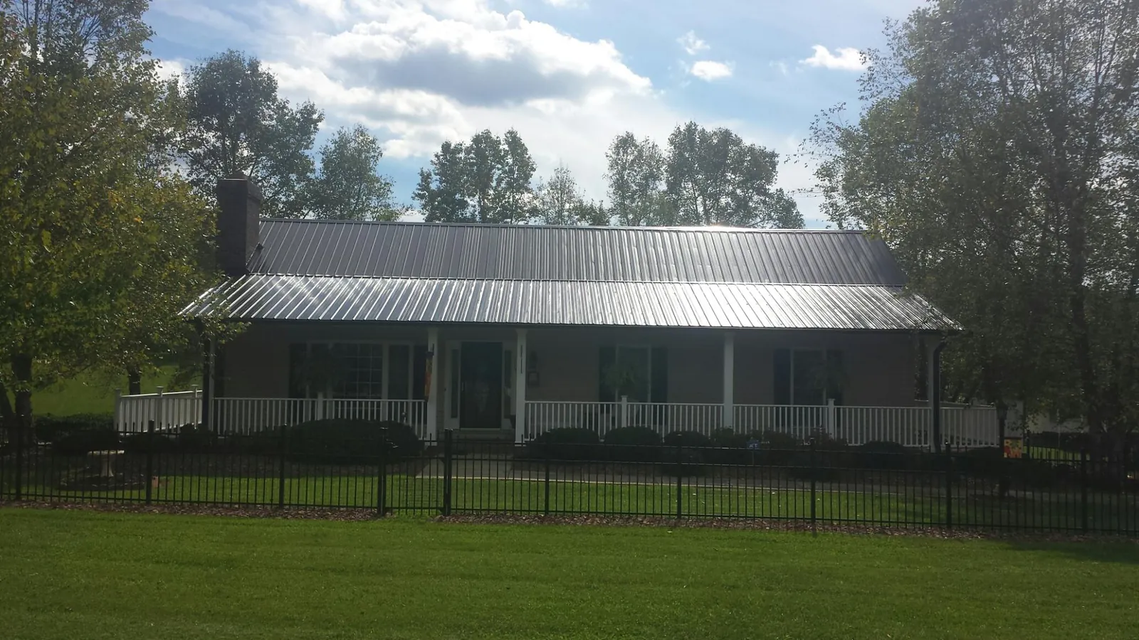 Gray metal roof on a brick ranch with a full width front porch — Gutter Guard Installation work by our crew in Waddy