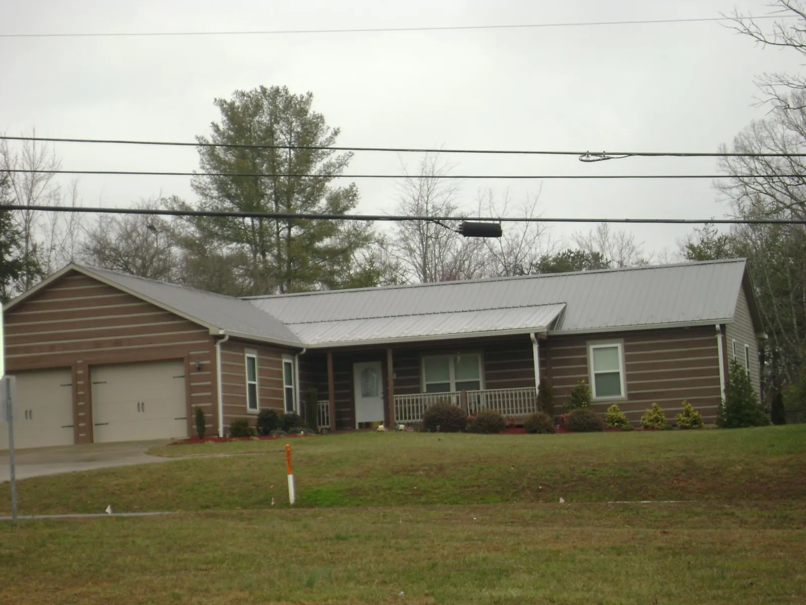 Gray metal roof on a log sided ranch home with a front porch in Waddy