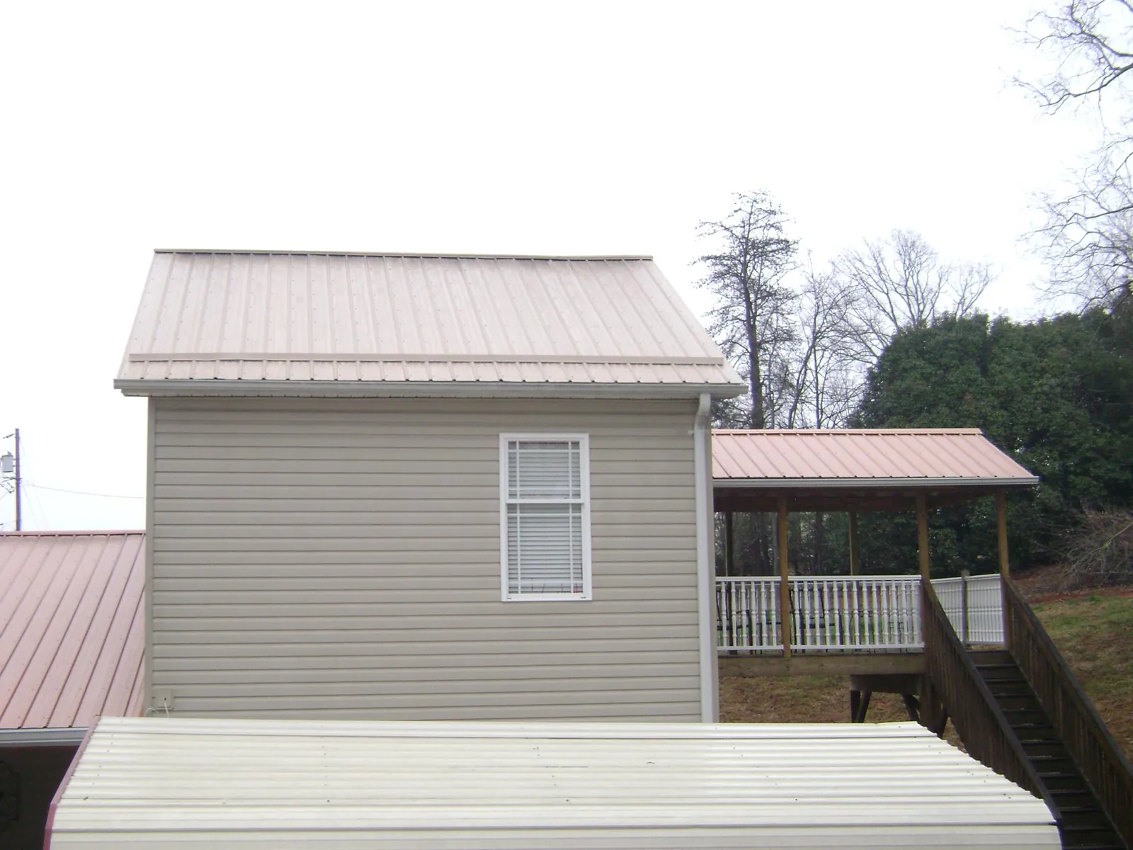 Tan metal roofs on a two story addition and attached porch, from a Roof Replacement job in Waddy
