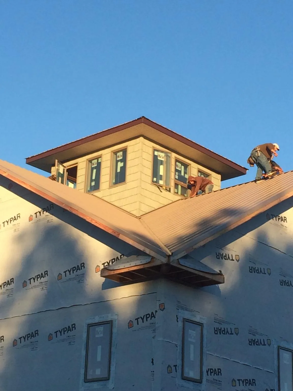 Roofers working around a rooftop cupola on a new metal roof at sunset — Roof Waterproofing in Waddy by Roofing Brothers